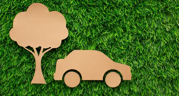 figurines en carton d'un arbre et d'une voiture sur de l'herbe