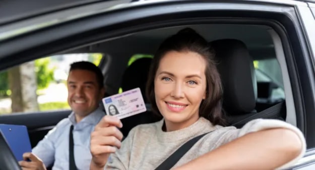 couple dans une voiture avec jeune femme qui montre son permis de conduire