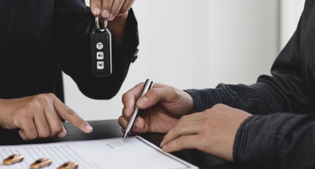 personnes qui signent un contrat avec clé de voiture en main 